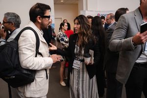 Professionals networking at a conference event, engaged in conversation in a busy hallway setting.