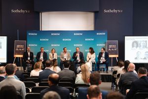 Panel discussion at Sotheby's Bisnow event with seven speakers seated on stage before an audience.