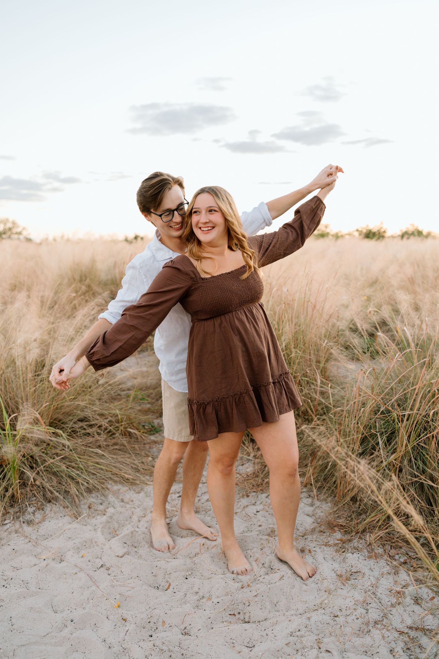 Lifestyle couple session featuring a playful embrace in tall grass during golden hour.