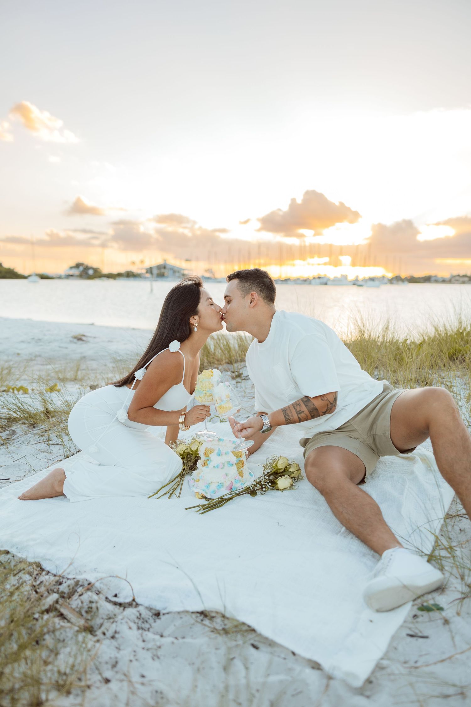 Lifestyle couple portrait of a couple sitting together on a blanket at the beach during sunset.