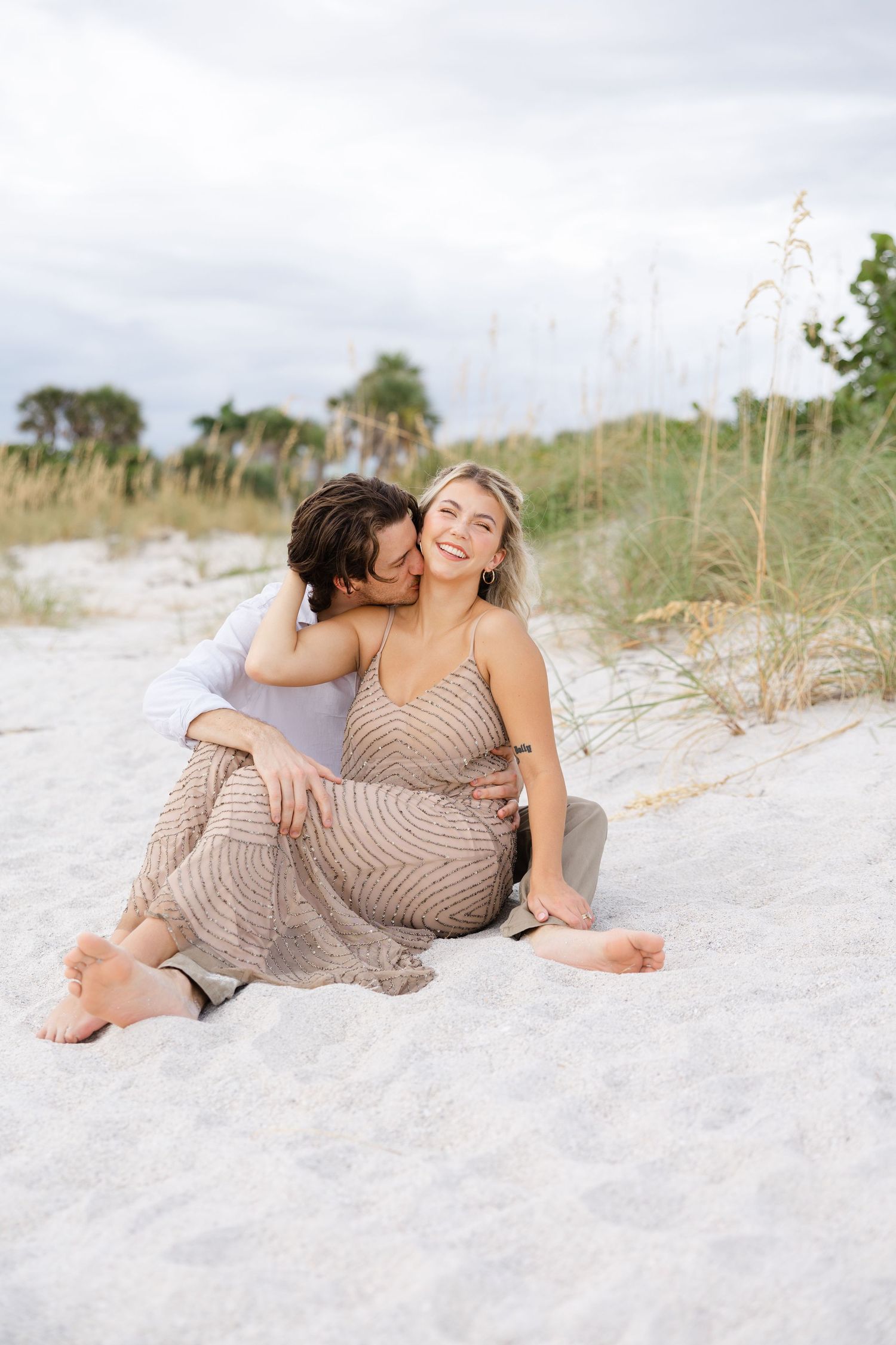 Romantic lifestyle couple portrait of a couple lying together on the beach in soft natural light.