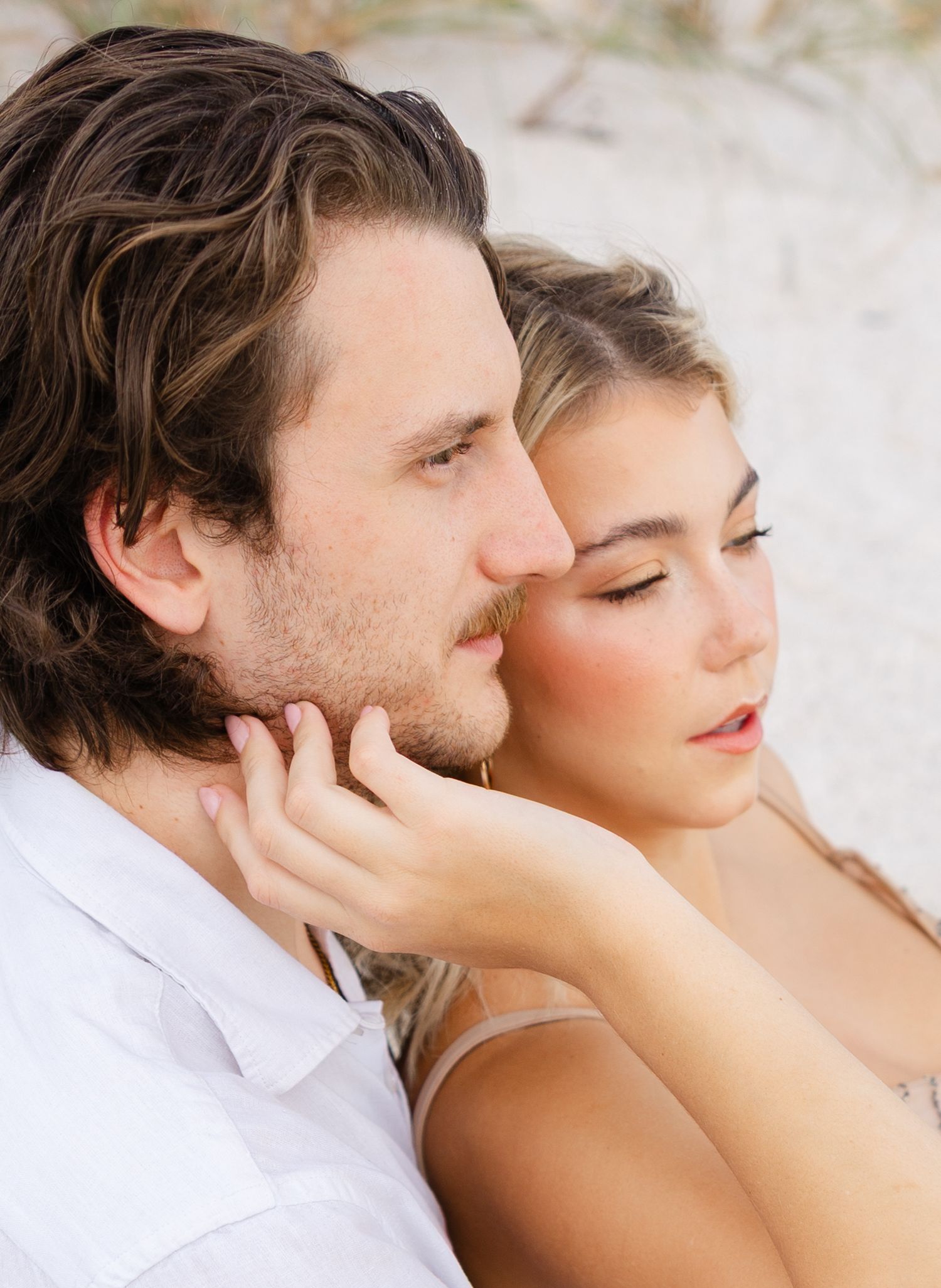 Romantic lifestyle couple portrait of a couple lying together on the beach in soft natural light.