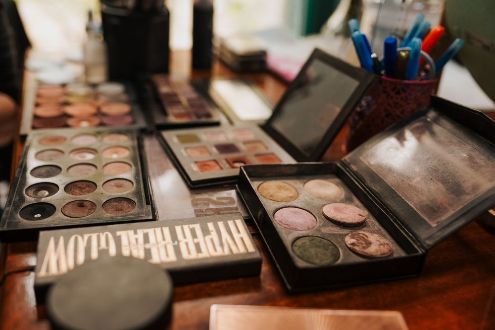 Collection of professional eyeshadow palettes and makeup products arranged on wooden vanity table.