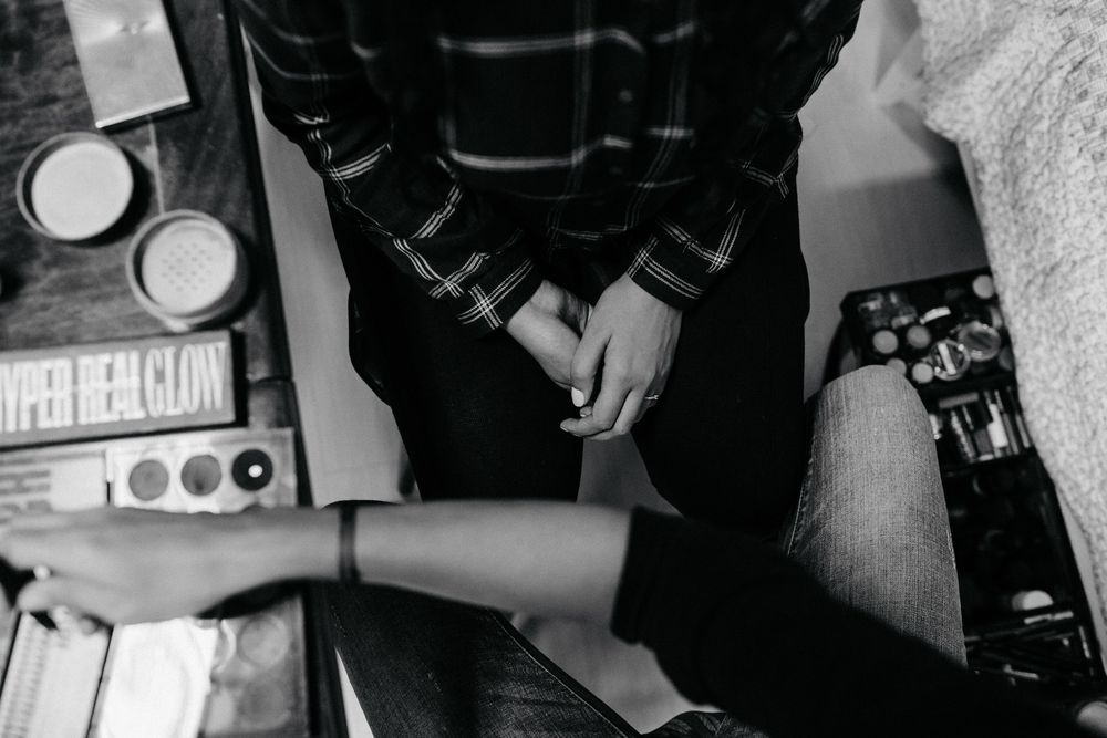 Black and white overhead shot of bride getting nails done at makeup table with beauty products.