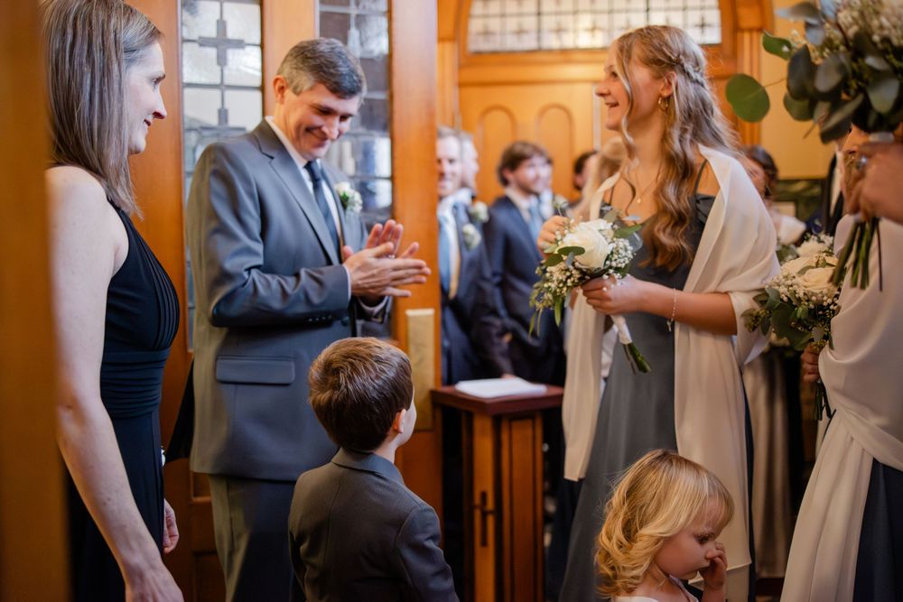 Wedding guests and bridal party exchanging warm greetings inside an elegant wood-paneled church ceremony venue.