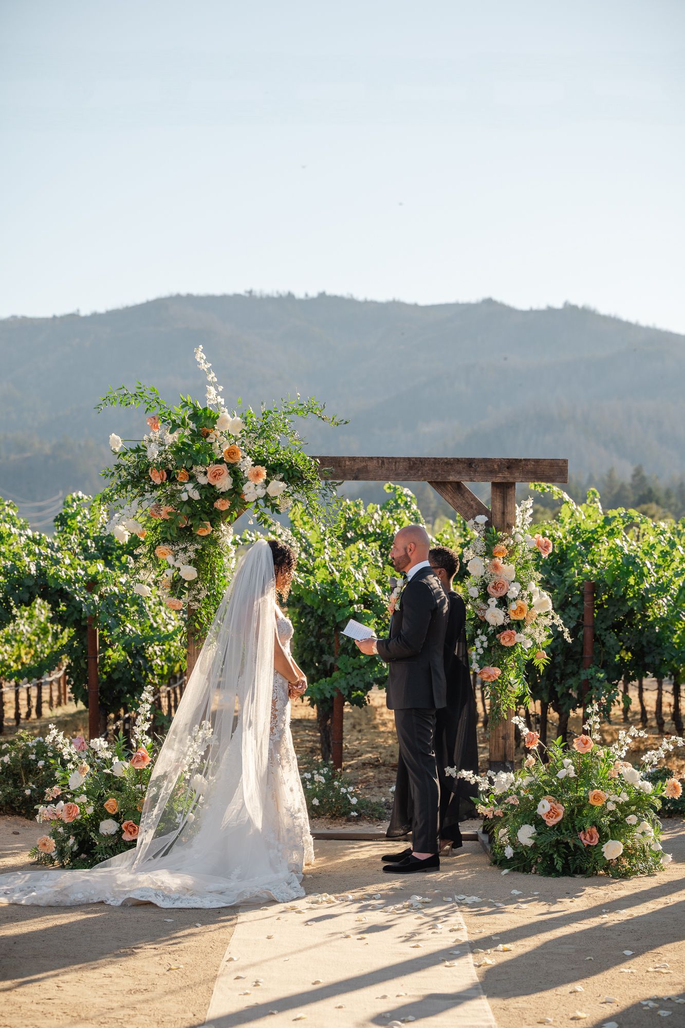 Bride and groom share first dance on checkered floor under string lights at elegant outdoor evening wedding reception.