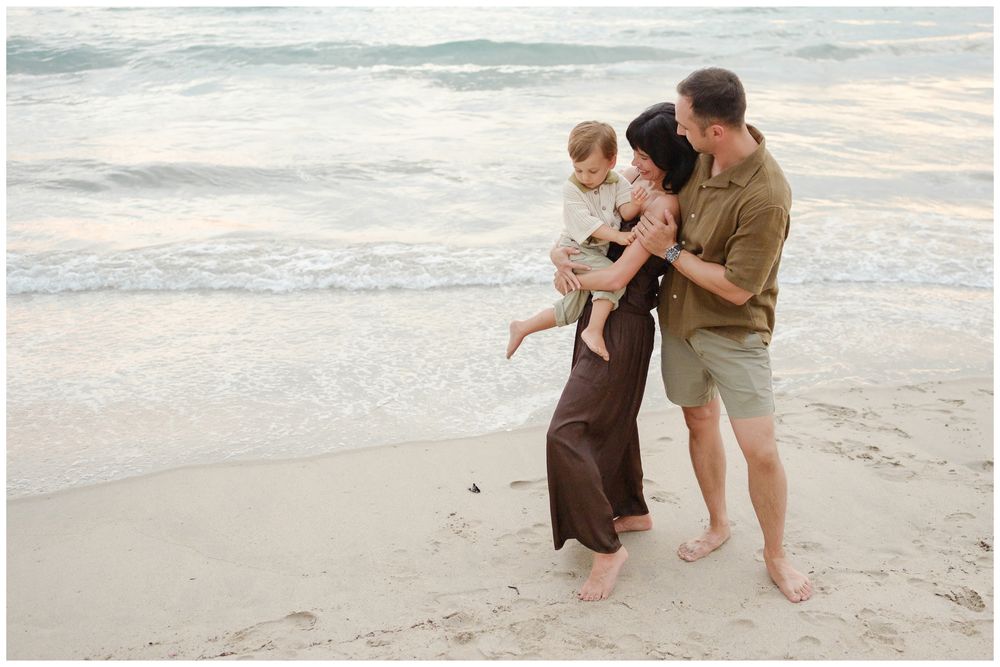 Family portrait of parents lifting their child during a beach family photo session.