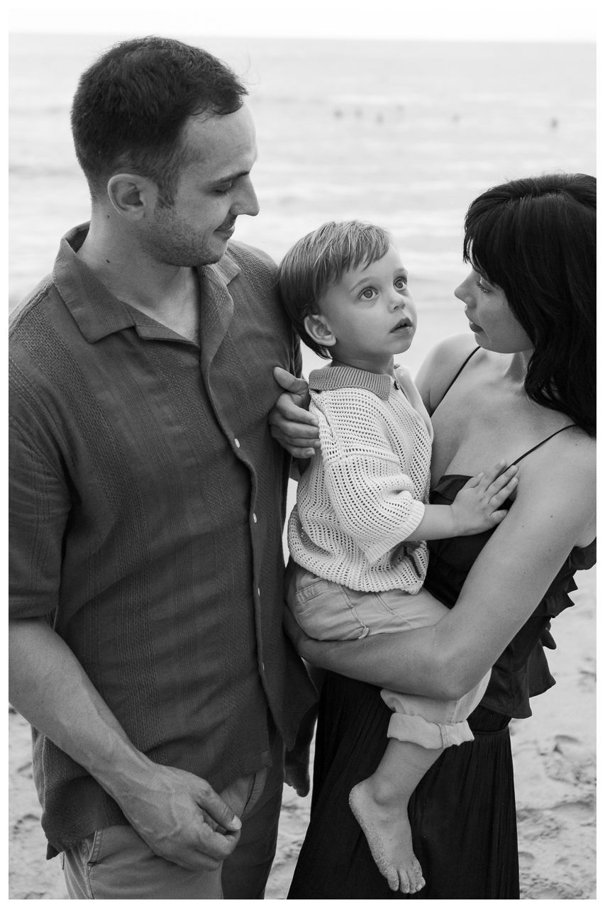 Black and white family photo session in Puerto Vallarta with parents and toddler on the beach.