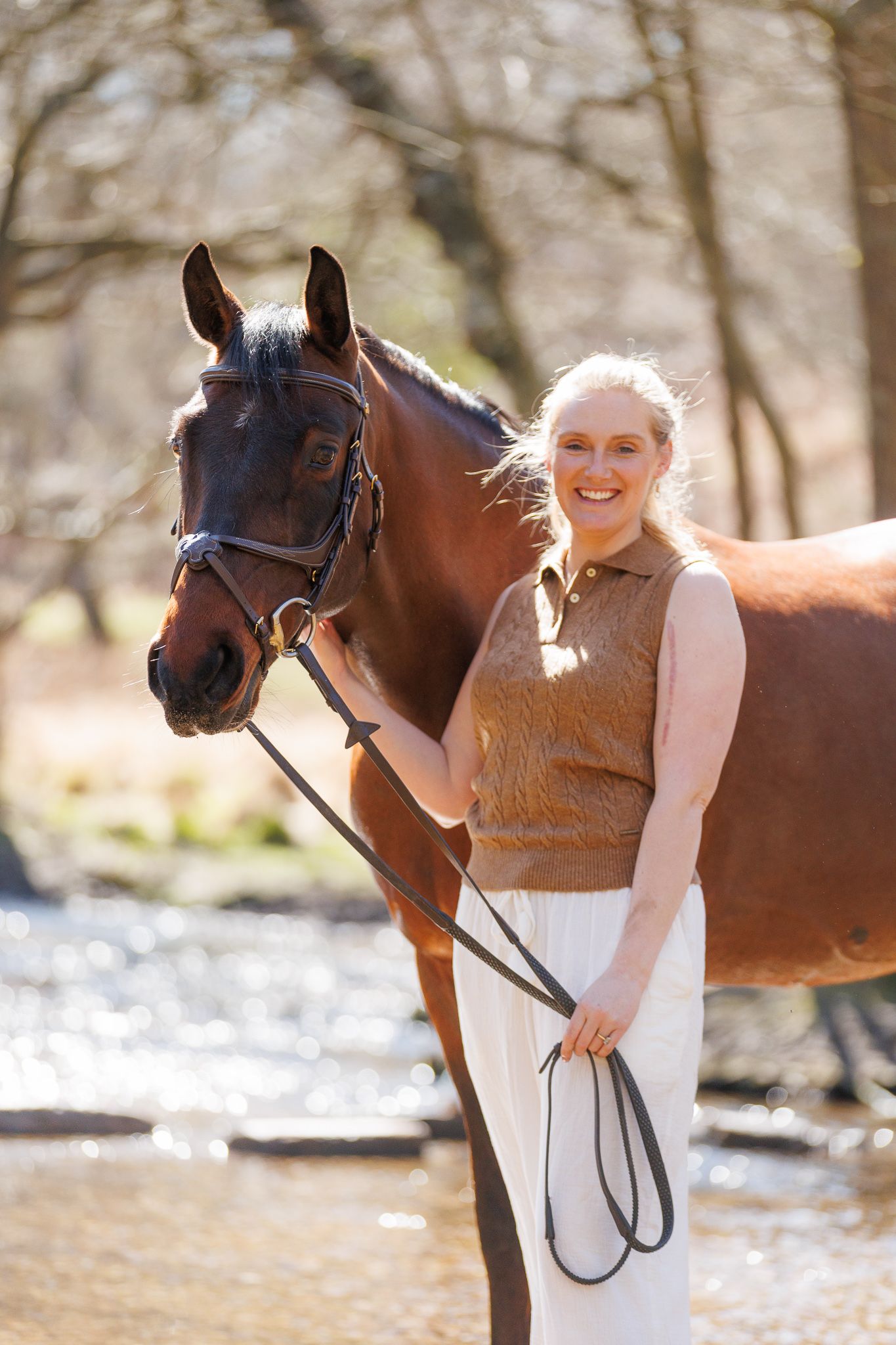 Woman with a paint horse among daffodils by a wooden fence in a lush green countryside setting.