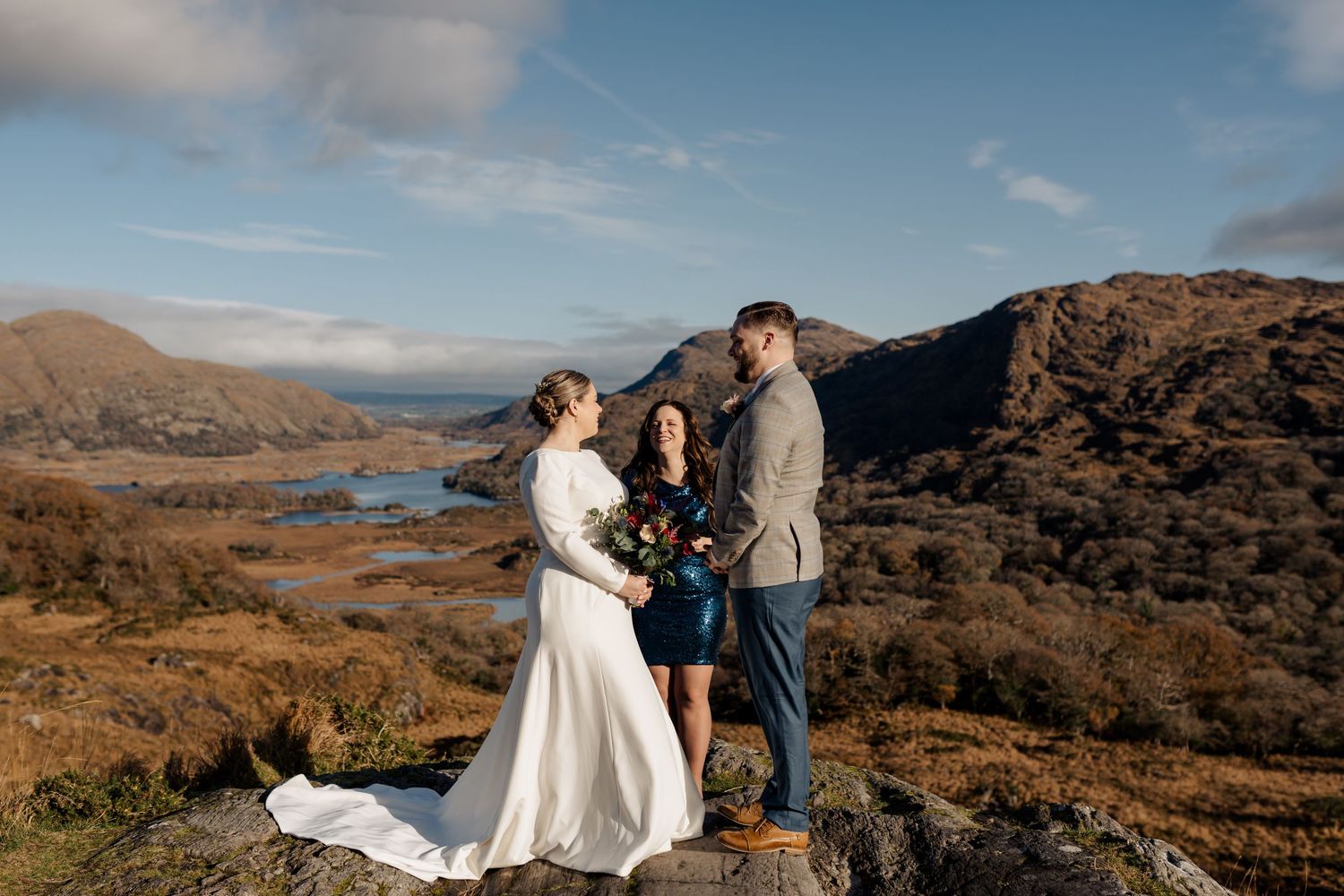 Wedding ceremony on mountain top overlooking lakes and rugged landscape.
