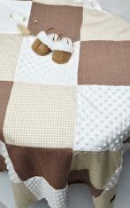 Soft patchwork baby quilt in mint green and white with a plush bunny stuffed animal on a cozy bed.