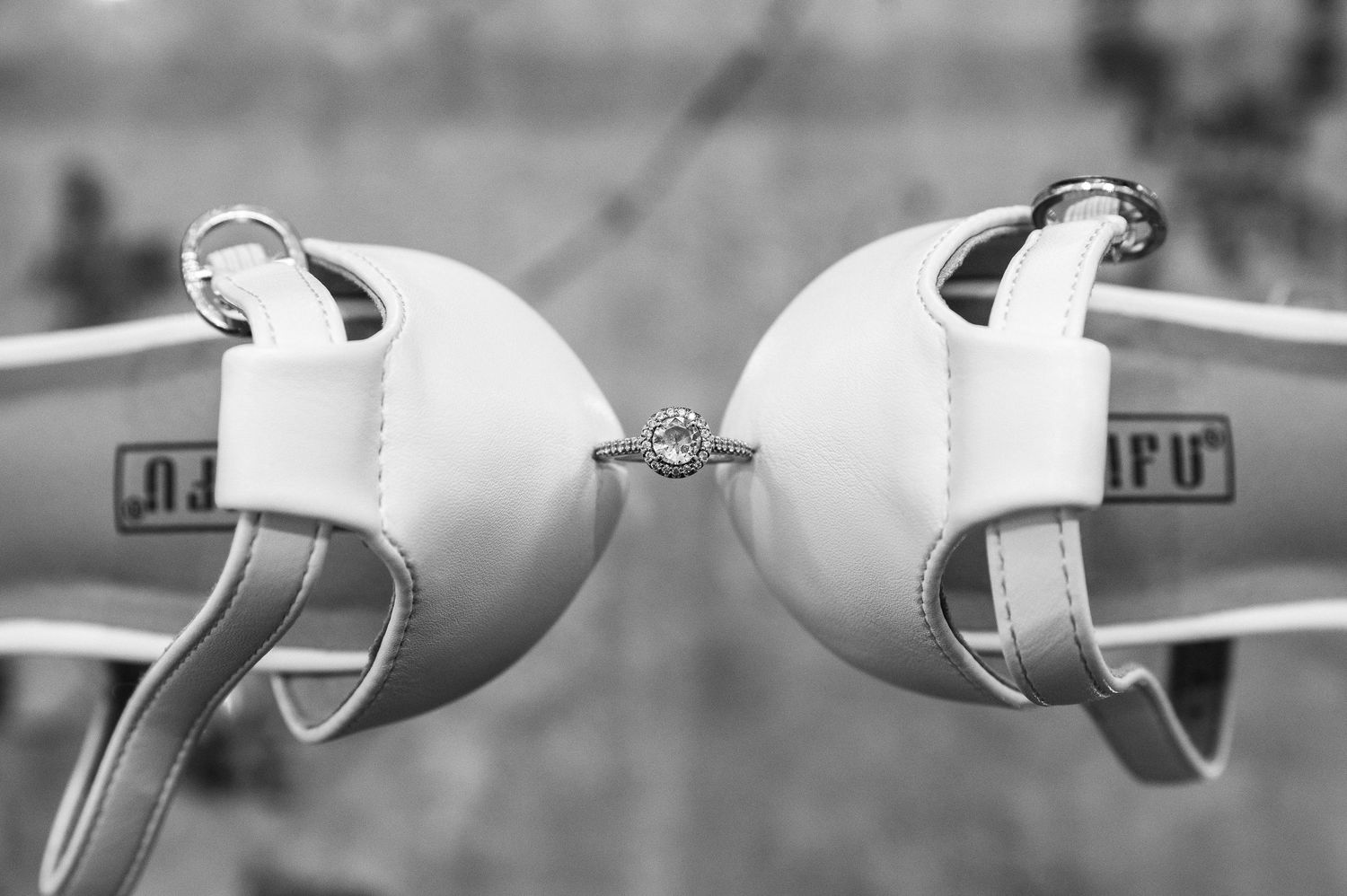 Black and white photo of a diamond engagement ring balanced between two boxing gloves, symbolizing love and commitment.