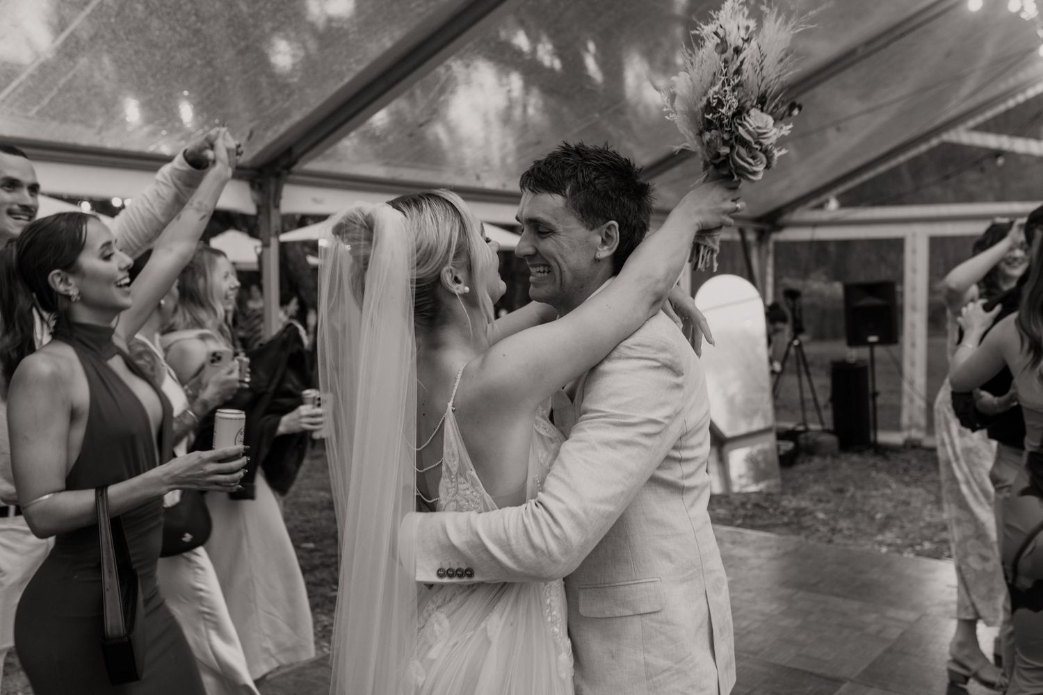 Black and white photo of a bride and groom sharing a kiss on their wedding day, bride wearing veil.