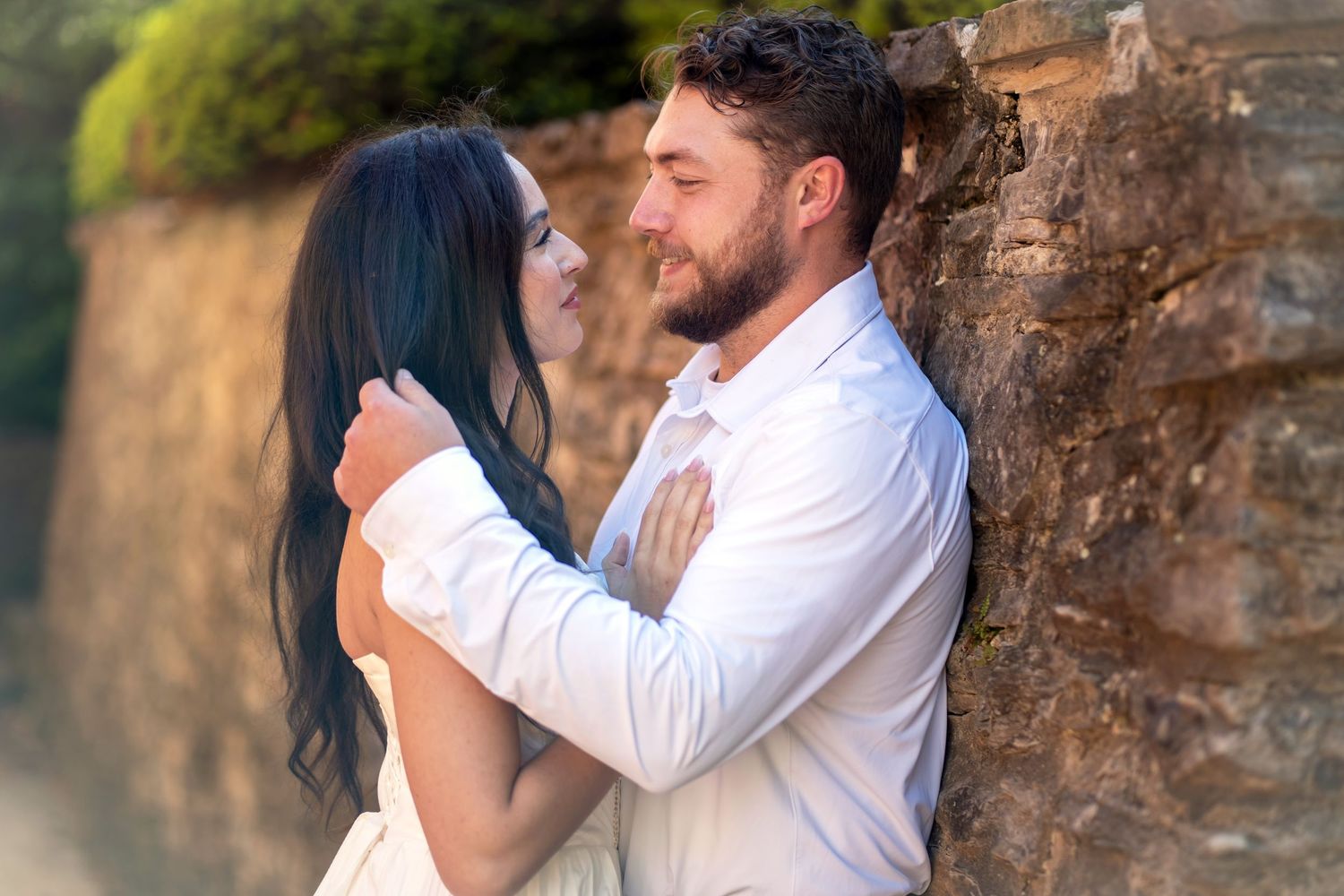 Romantic couple embracing near a stone wall outdoor Jeffrey Mansion for their Engagement Session
