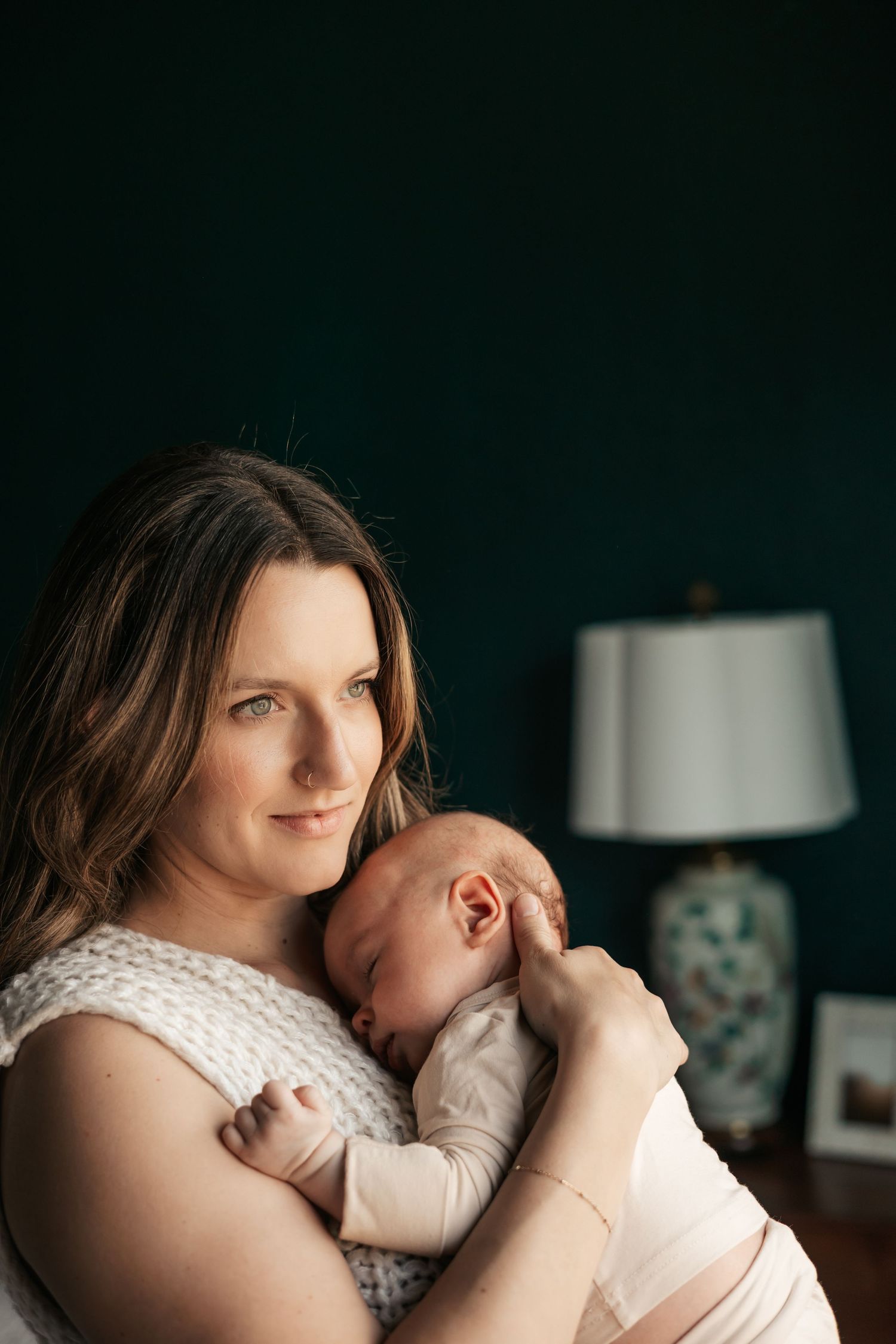A mother tenderly holds her sleeping newborn baby against her chest  | Newborn Photographer in Broomfield Colorado