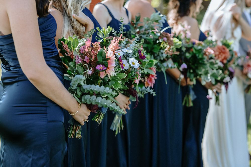 Close up of bridesmaids and bride in navy blue dresses holding bouquets. Southern New Hampshire Maine wedding photographer