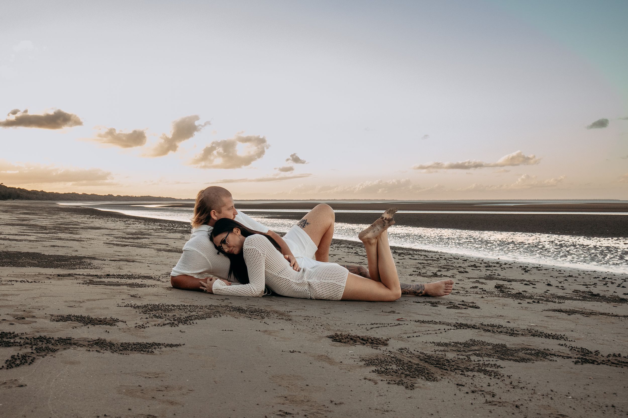 A couple lying on the beach at sunset, relaxing into each other