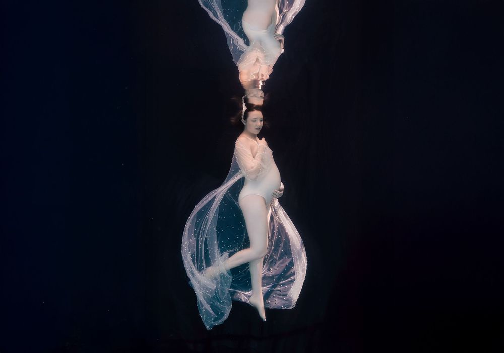 A ballet dancer in a flowing white dress performs an elegant leap against a dark background.