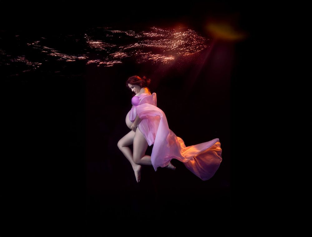 A series of glowing orange and pink jellyfish float gracefully in dark water creating an ethereal underwater scene.