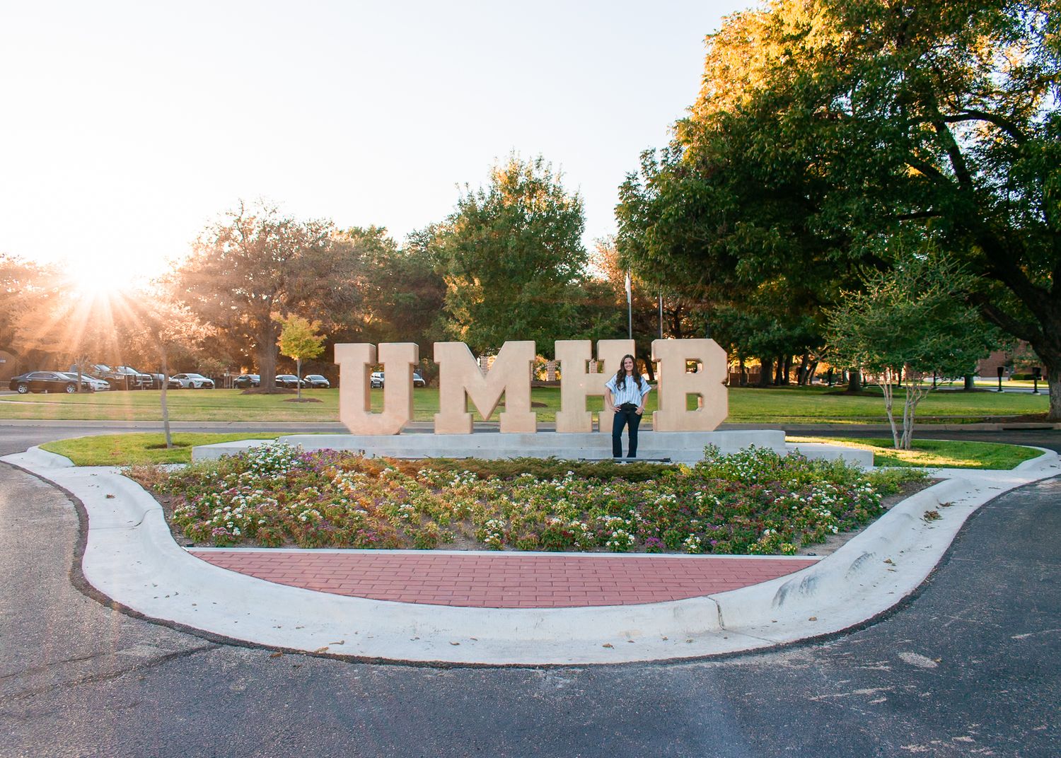 A Masters student at the University of Mary Hardin-Baylor poses at the UMHB sign in Belton, TX.