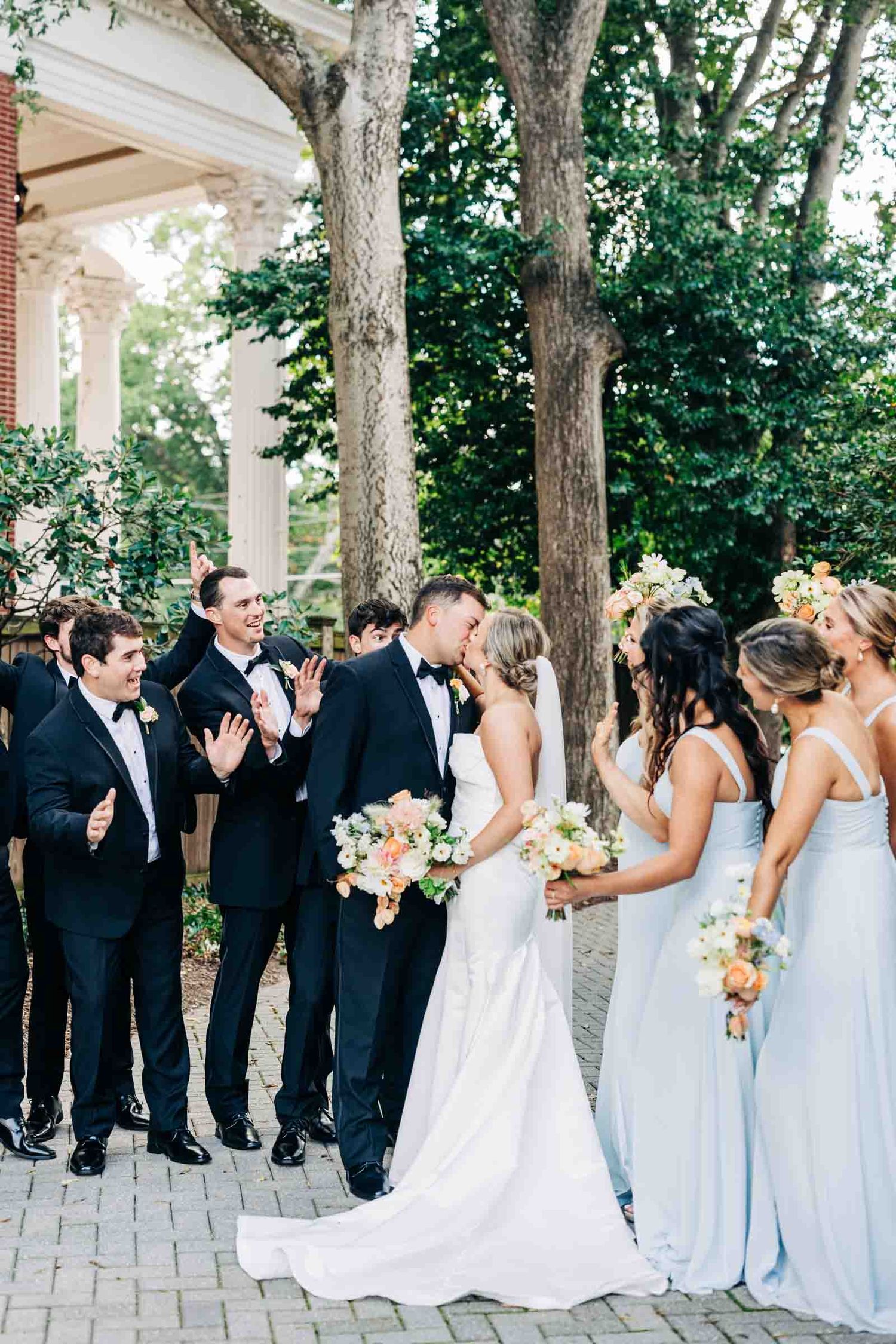 Wedding party in formal attire gathered outdoors with pale blue bridesmaid dresses and classic black tuxedos Athens GA 255 Milledge