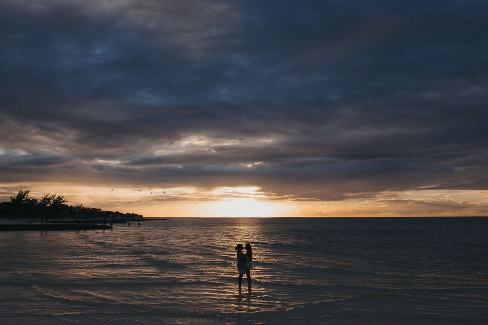 A lesbian couple sharing a quiet moment together after a sunset proposal on the beach in Holbox.