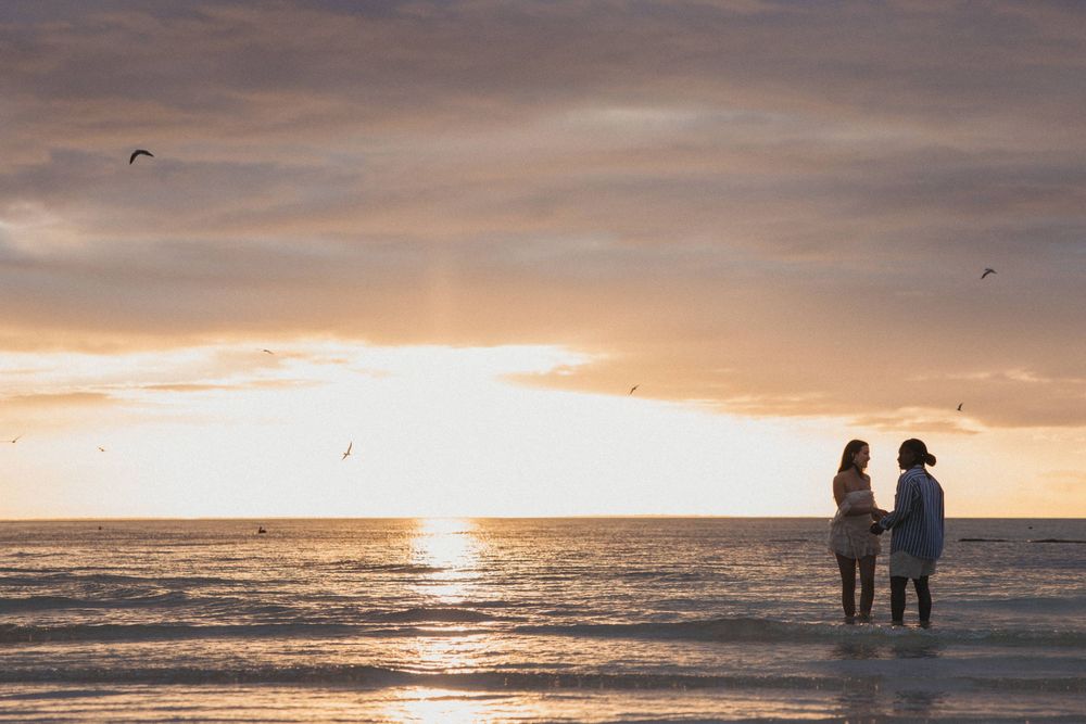 A couple of lesbians holding each other during a surprise proposal at sunset on the beach in Holbox.