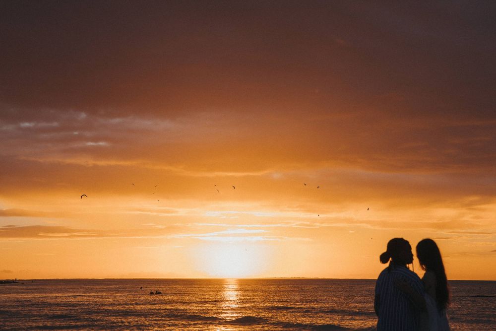 A gay couple silhouetted against a vibrant sunset in Holbox after their proposal photo shoot.