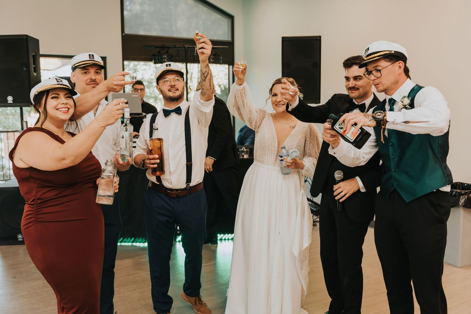 Wedding party members dance and celebrate together on a dance floor at a reception.