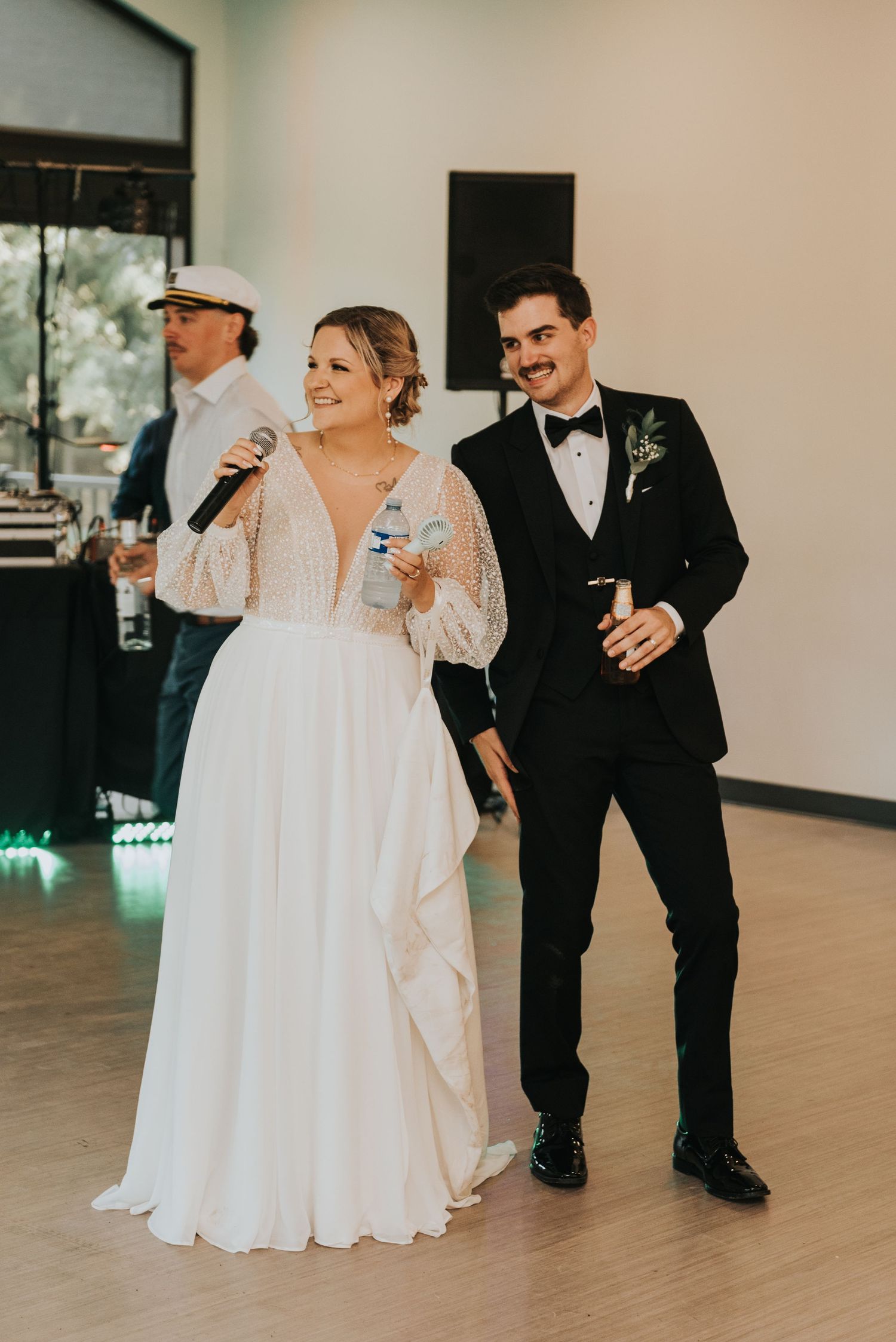 A wedding reception moment with a couple in formal attire sharing speeches and drinks on the dance floor.