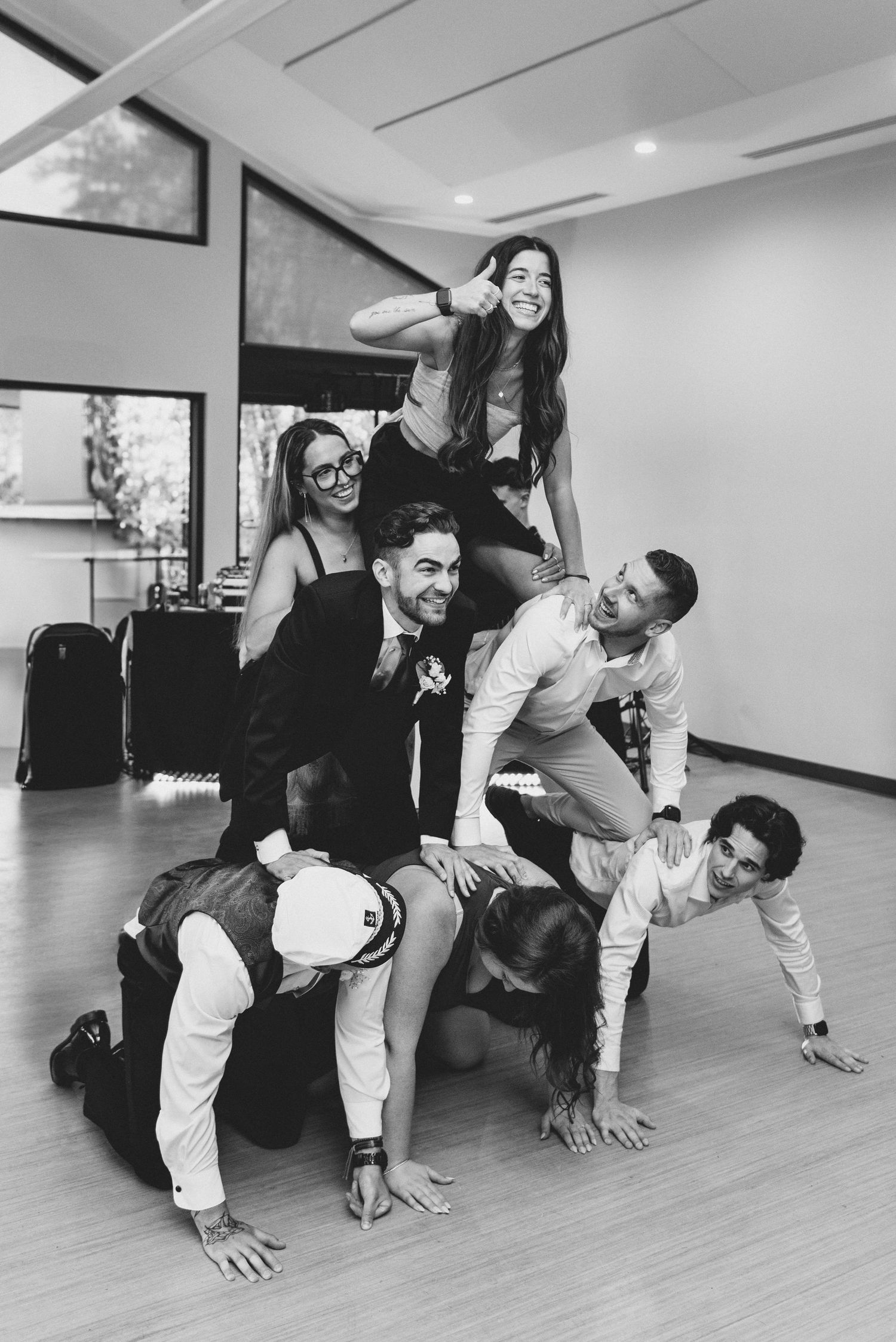 Wedding party members crawling in a line formation on a hardwood floor.