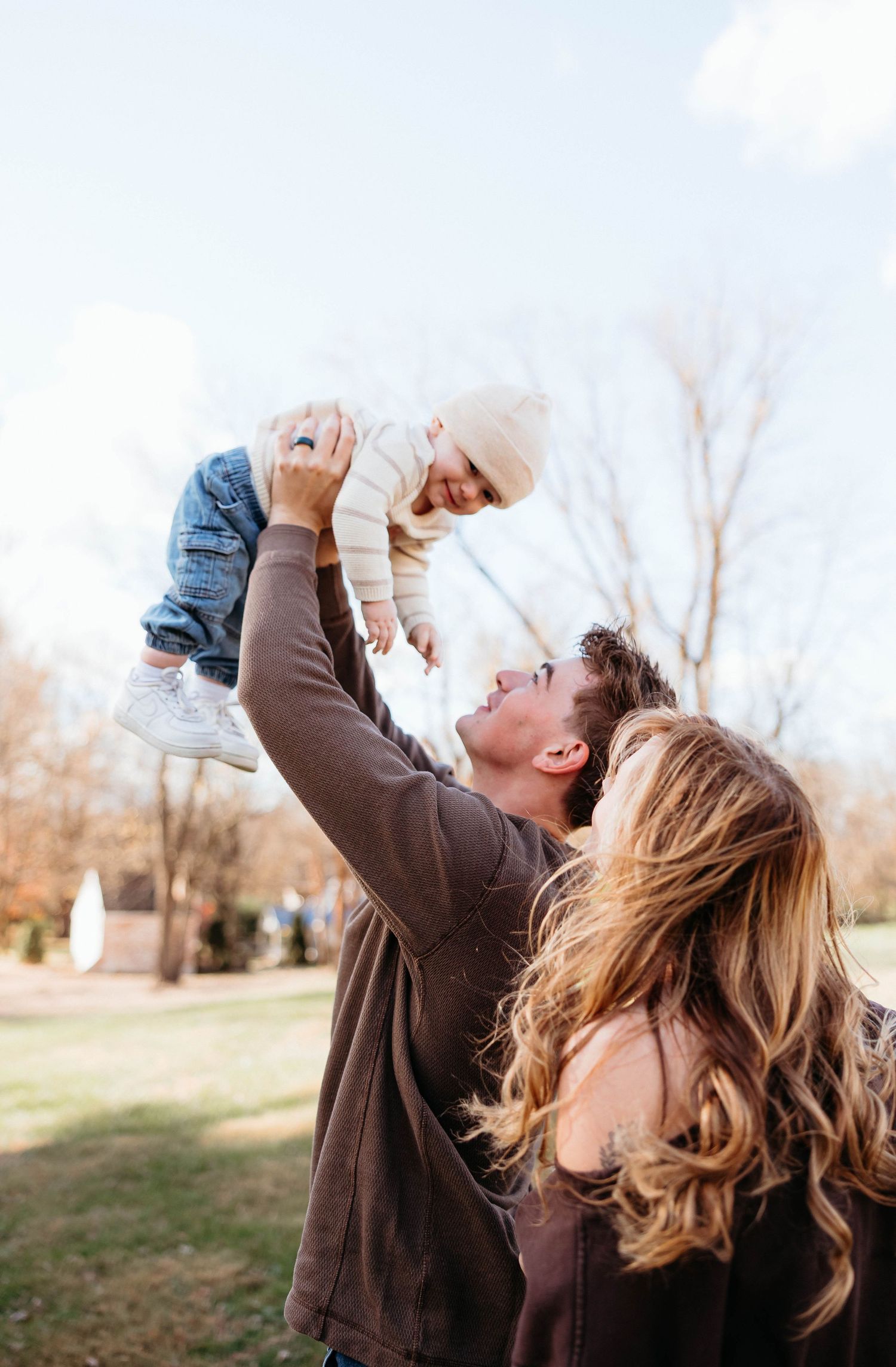 Parent playfully lifting child in the air during outdoor family photoshoot.