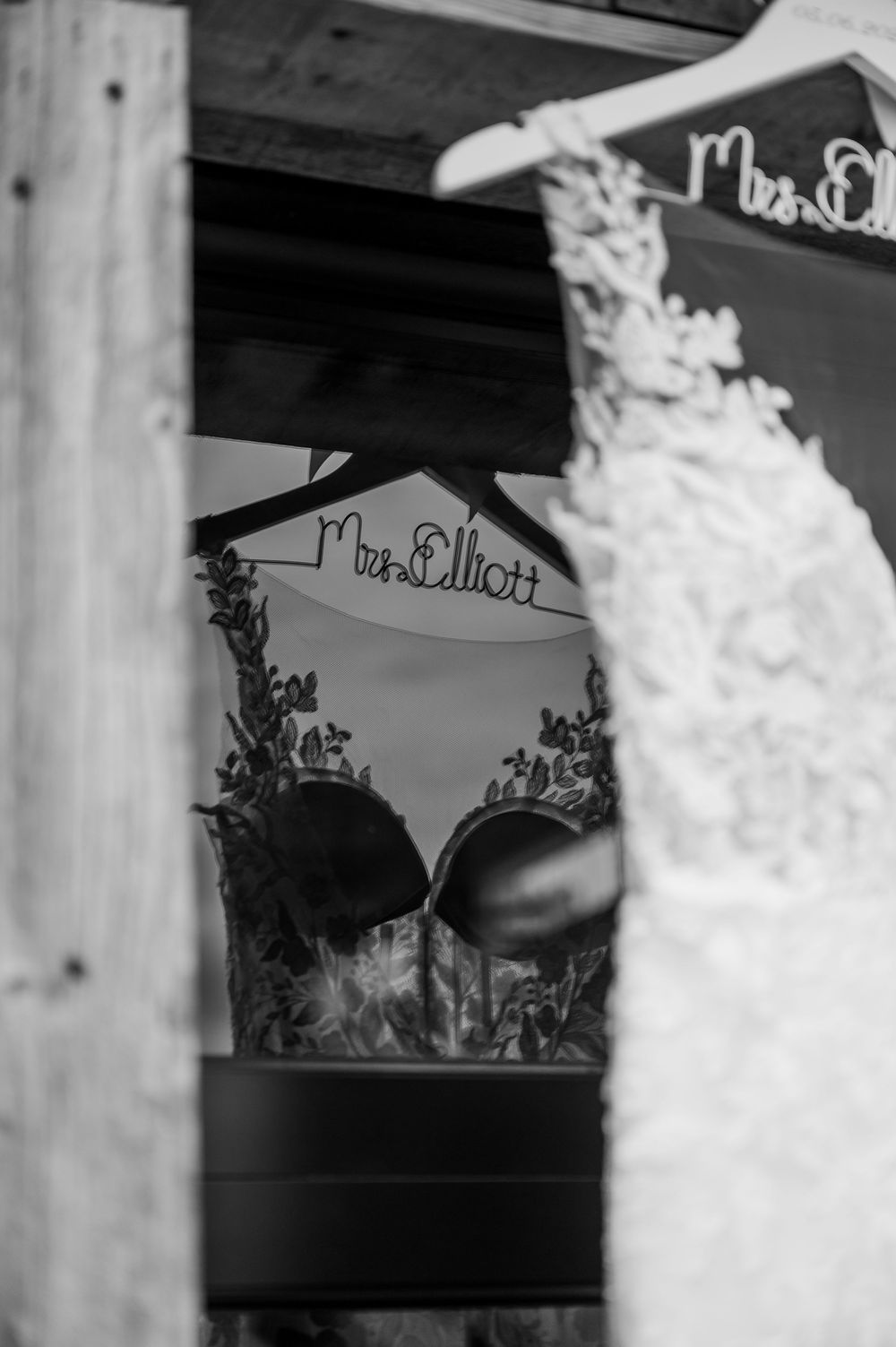 Black and white detail of a rustic wedding sign and decor through a wooden frame.