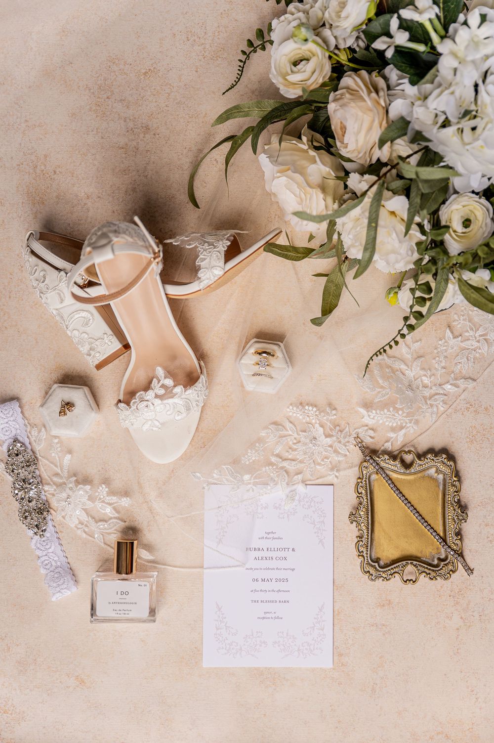 Wedding details including white floral arrangements, invitations, and delicate lace on a beige surface.