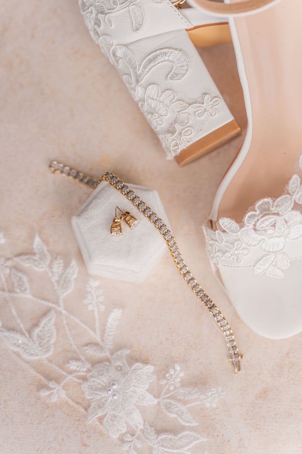 Delicate bridal jewelry with rhinestones displayed on white lace fabric.