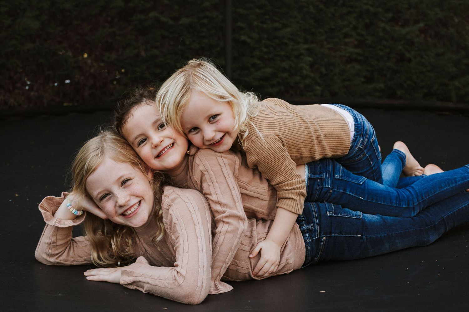 Unposed family photography of siblings lying together and laughing during a relaxed family photoshoot in Gloucestershire