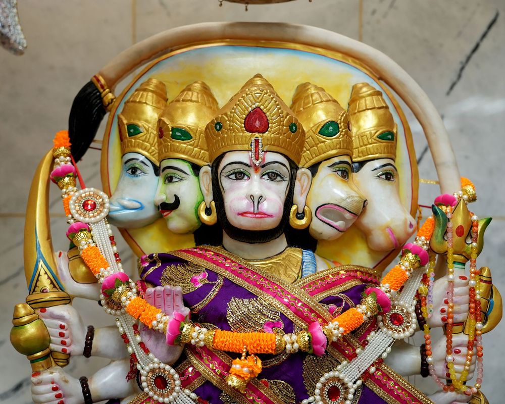 Colorful Hindu deity statues with golden crowns and ornate decorations displayed in a temple setting.