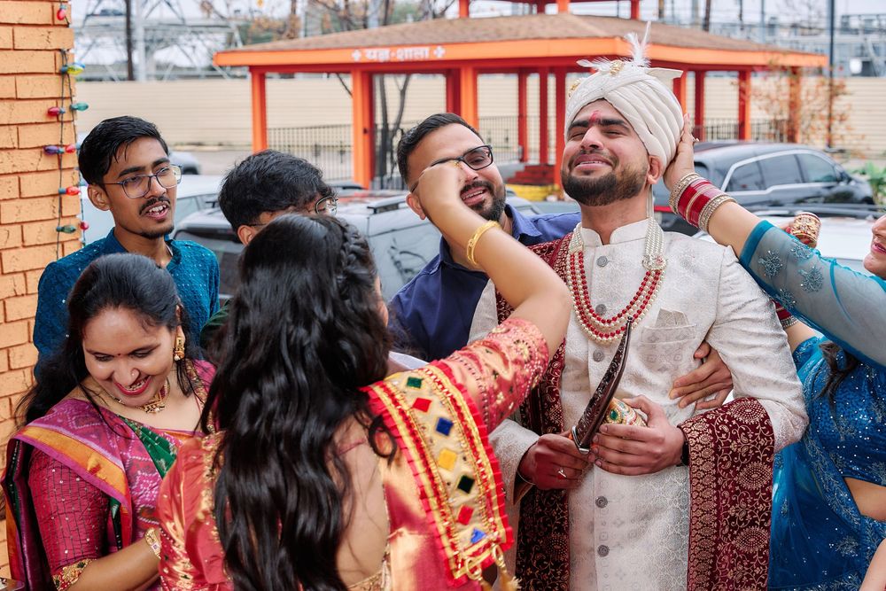 Wedding guests celebrating with colorful traditional outfits against brick wall backdrop.