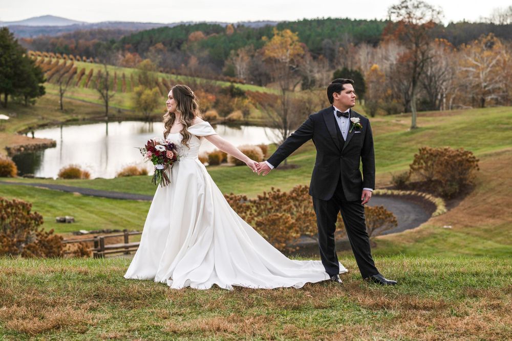 Newlywed couple poses in romantic fall vineyard settings with rolling hills and autumn colors in the background.