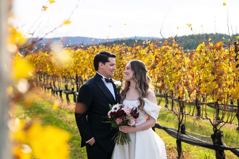 Romantic couple embraces in autumn vineyard with golden yellow foliage during wedding photo session.