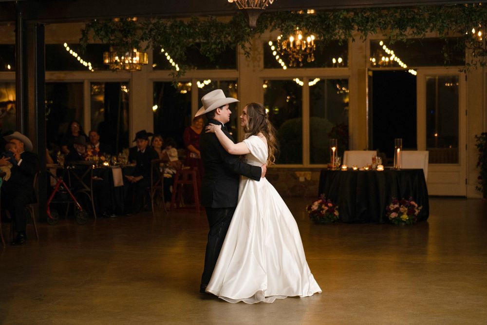 A couple shares their first dance under twinkling lights in an elegant reception hall.