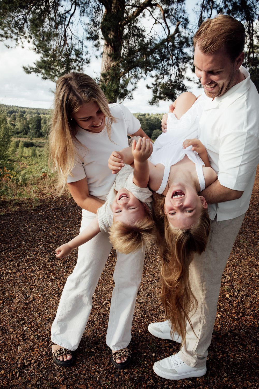 Fun moment with a mum and dad playing with their children - tipping them upside down to make them laugh.