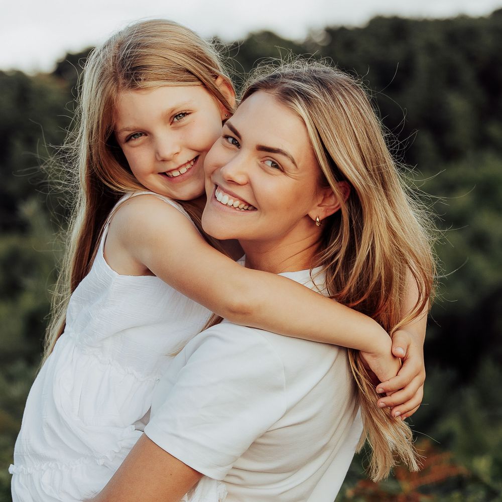 Natural moment of a mum holding her young daughter in the golden sunshine.