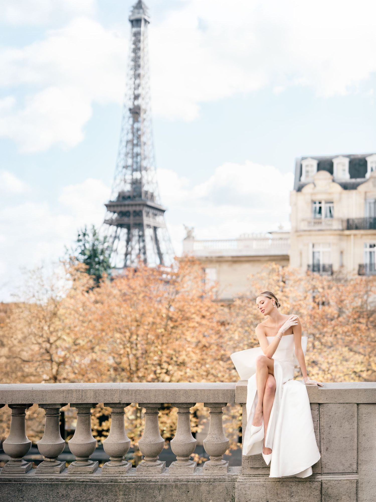 Elegant bridal photo session near the Eiffel Tower in Paris during autumn with golden foliage in the background.