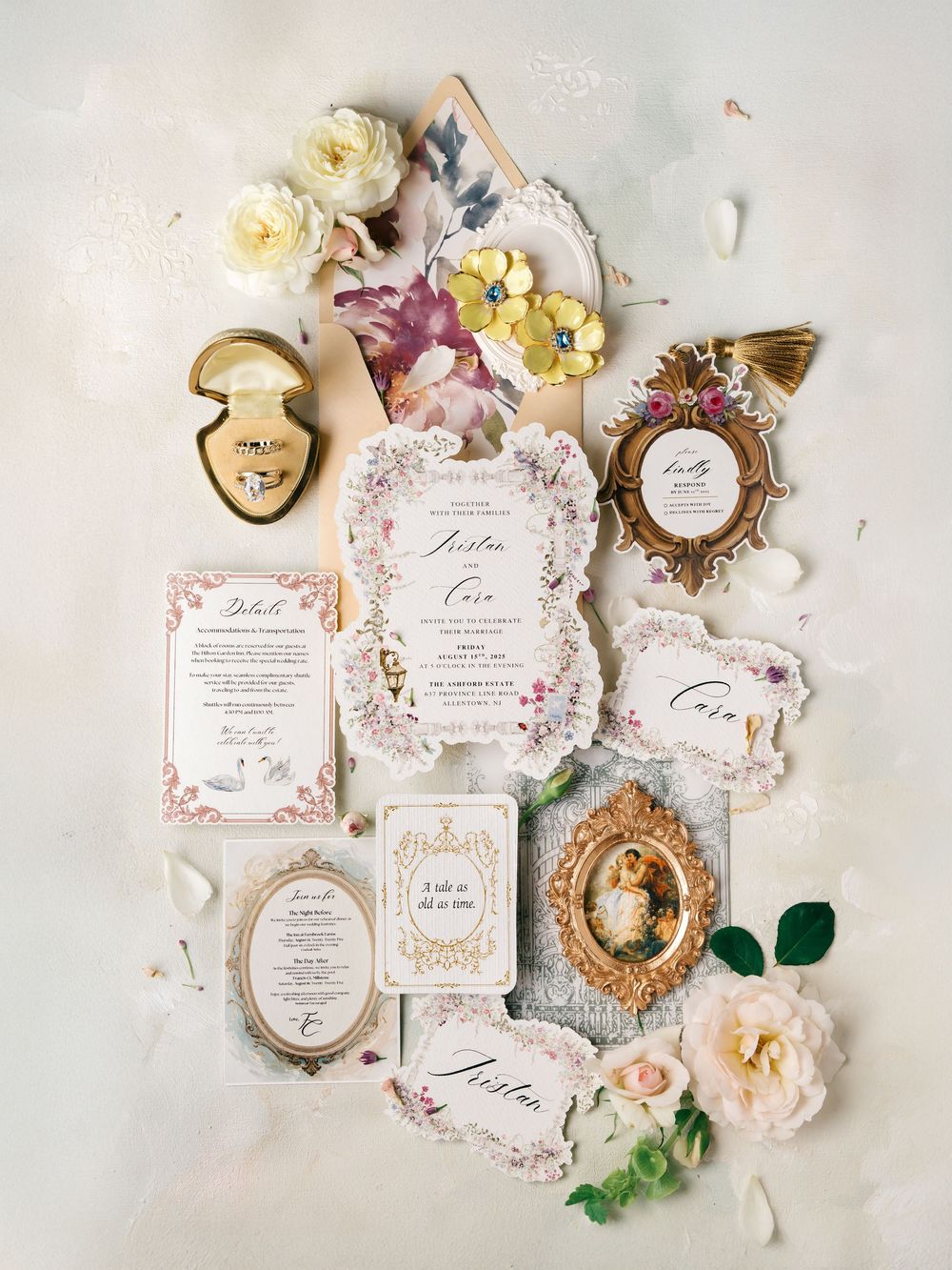 Elegant wedding invitation suite with floral details, vintage frames, and delicate pink roses arranged on white textured surface.