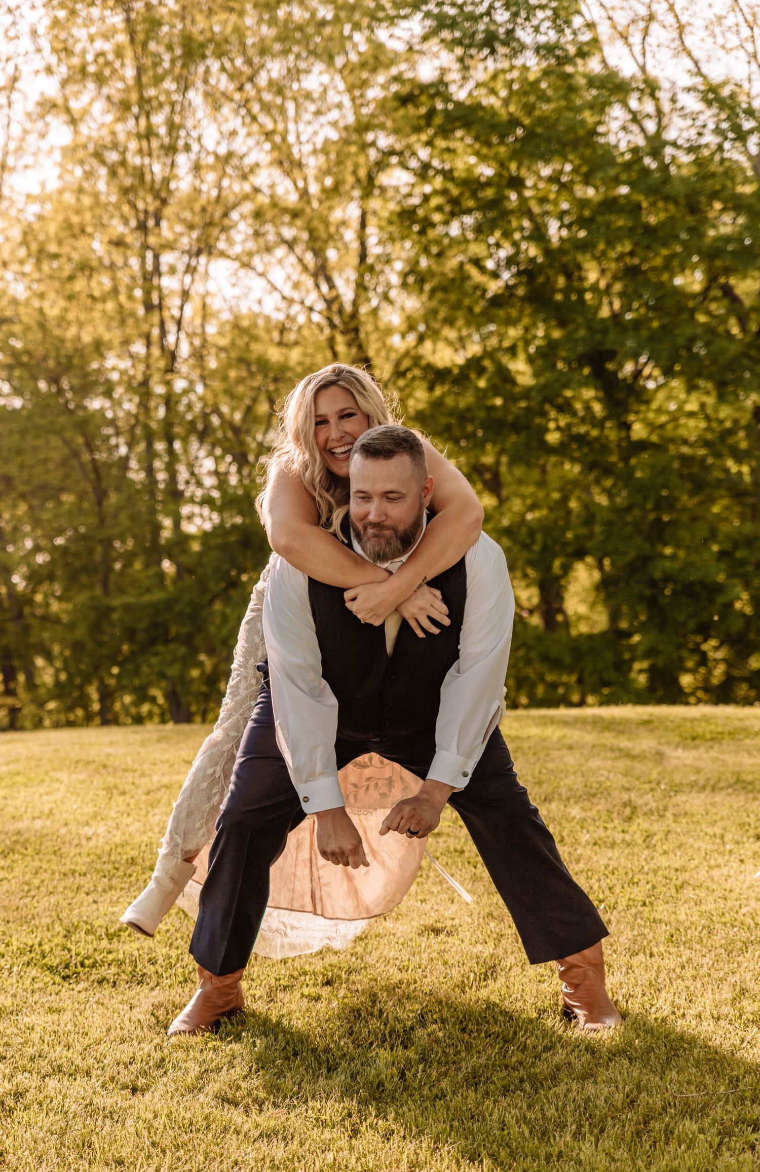 Playful wedding couple poses in a sunlit meadow during golden hour.