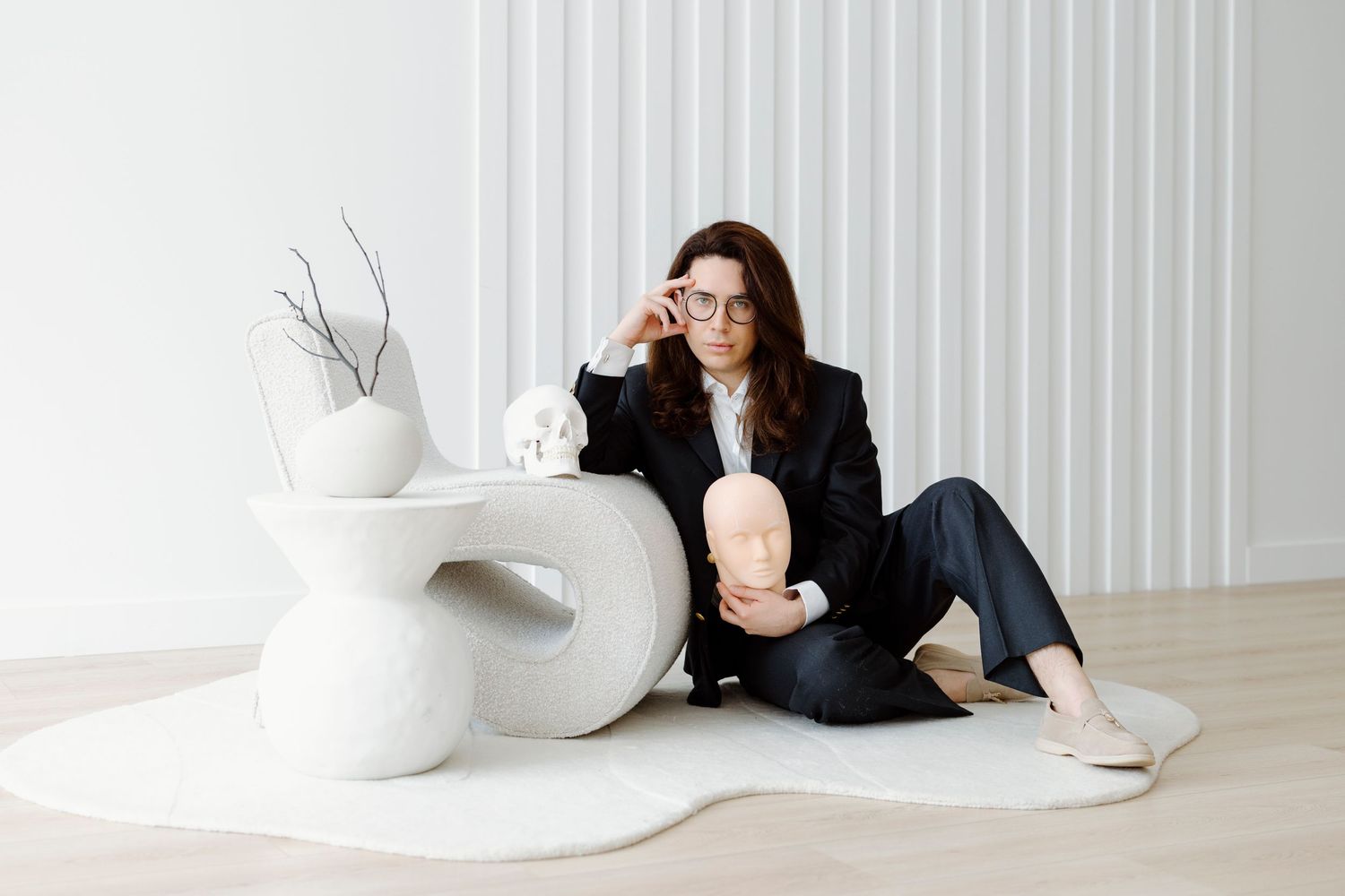 A sequence of photos showing a person lounging and interacting with a large white sculptural cushion on a light floor.