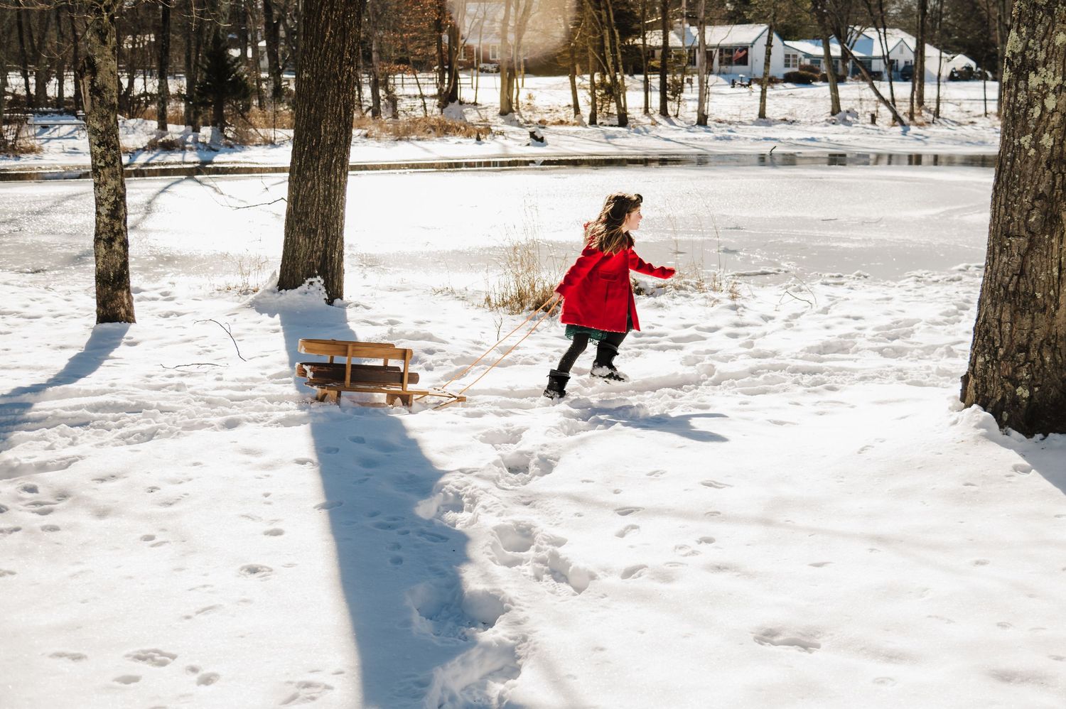 A person in a red jacket sledding down a snowy hill on a winter day.
