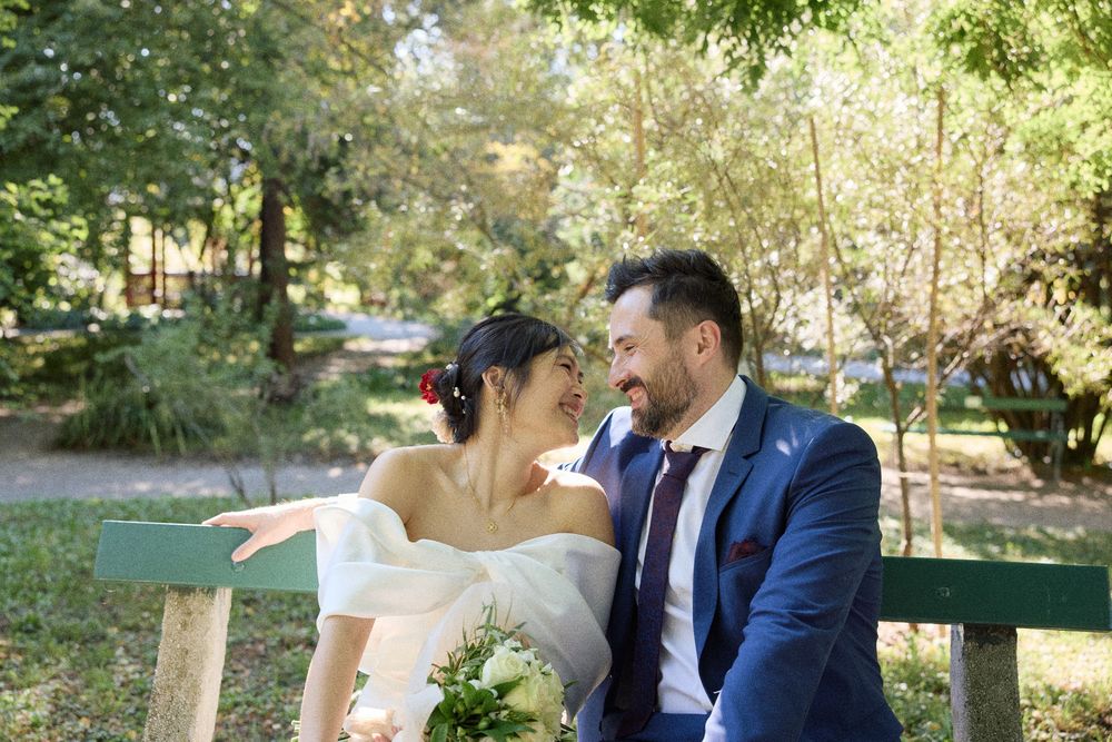Wedding couple sharing joyful moments in a sunlit garden setting.