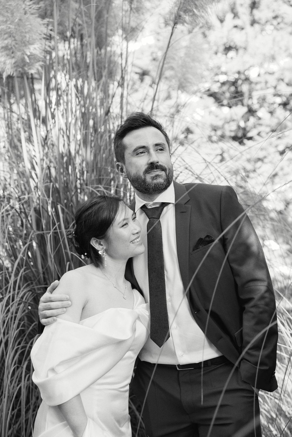 Couple sharing intimate moments among tall reeds in black and white photography.